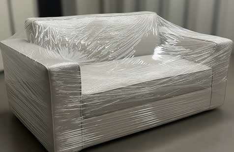 Sofá de dos cuerpos completamente embalado con film protector stretch, listo para un traslado seguro en servicio de mu